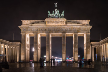 Tourists marvel at the Brandenburg Gate, Berlin, Germany, at night.