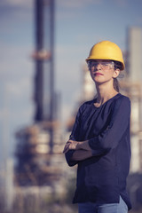 woman oil engineer is standing in front of a refinery