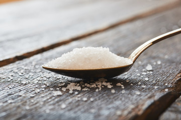 Sea salt in a spoon on wooden table