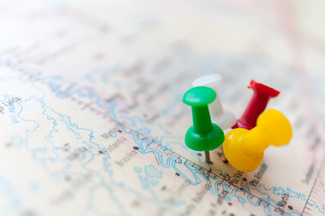 Travel destination points on a map indicated with colorful thumbtacks and shallow depth of field