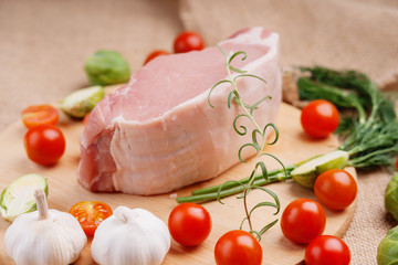 Raw pork on cutting board and vegetables 