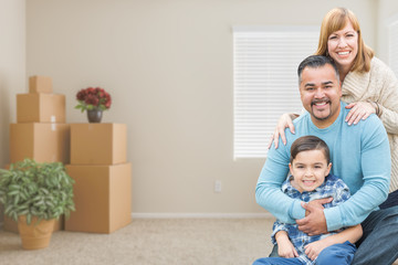 Happy Mixed Race Family with Son in Room with Packed Moving Boxes.