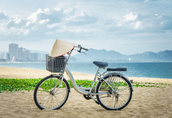 Bicycle parking in the beach sand. on handlebars Vietnamese hat hanging. Vietnam