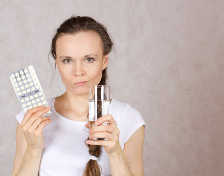 Young lady has a glass of water and pilss