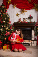 Obraz na płótnie Canvas Beautiful girl with gifts in a red dress near Christmas tree wi