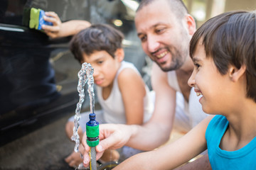 Young father and little sons washing ca