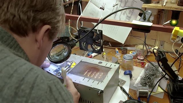 Engineer preparing motherboard of smartphone iphone to repair. White man in old workshop.