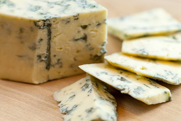 tasty sliced moldy cheese on wooden plate