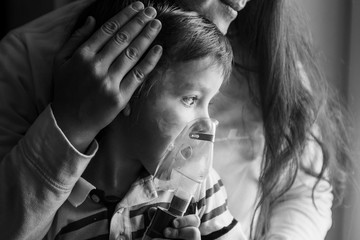 Young woman with son doing inhalation  a nebulizer at home