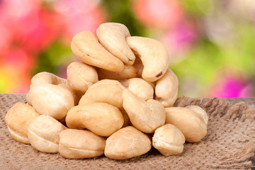 heap of cashew nuts on a wooden table with sacking and blurred garden background