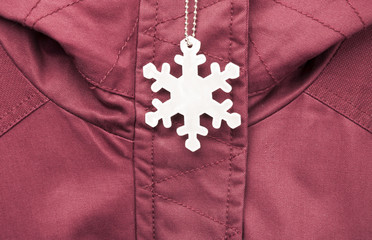 Cute white safety reflector in the form of snowflakes on the winter jacket. Necessary equipment to...