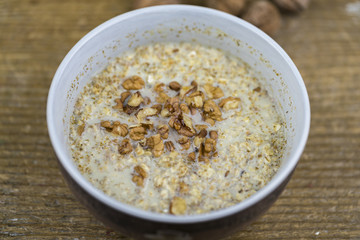 Closeup of bowl of porridge with healthy nuts on rustic wooden table