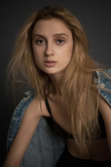 Portrait of sad beautiful young blonde woman in bra and jeans jacket