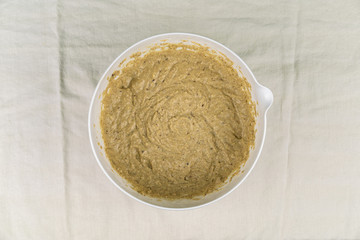 Overhead view of bowl of mixed dough on light-colored tablecloth