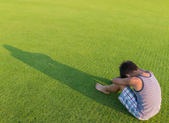 Sad lonely kid on green meadow
