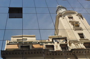 distorted view of the front of an old building downtown Buenos Aires mirrored in the glass front of another building