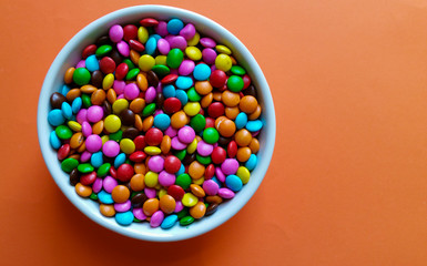White pot with sweet confetti with orange background