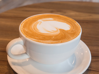 Delicious hot coffee in white cup on wooden table