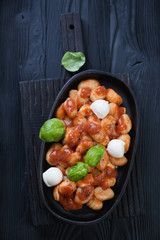 Italian potato gnocchi alla Sorrentina over black wooden surface