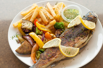Grilled trout on a plate with grilled vegetables