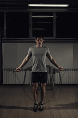 Fototapeta na wymiar Portrait of young male athlete skipping rope.