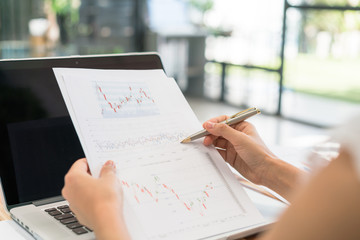 Business woman hand with Financial charts and laptop on the tabl