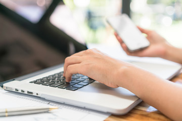 Closeup of business woman hand typing on laptop keyboard with mo