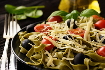 Spinach green pasta with olives, tomatoes and cheese.