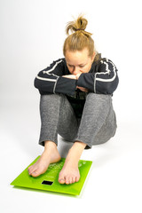 Girl sitting on floor looks sad on the scales