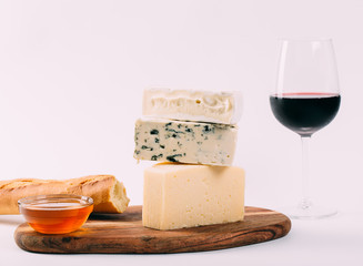 Still-life cheese platter with nuts, honey and wine on white background