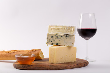 Still-life cheese platter with nuts, honey and wine on white background