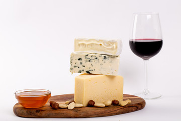 Still-life cheese platter with nuts, honey and wine on white background