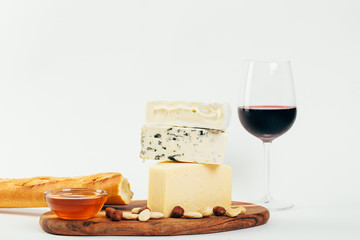 Still-life cheese platter with nuts, honey and wine on white background