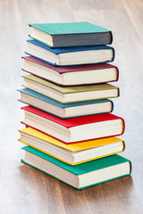 the lying multi-colored books on a wooden table.