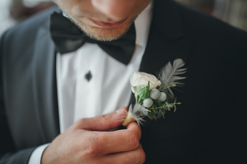young groom boutonniere in his hand closeup