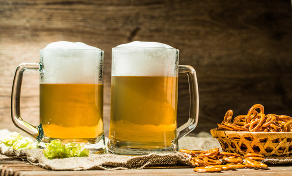 Couple beer mug with hop and pretzels on linen cloth