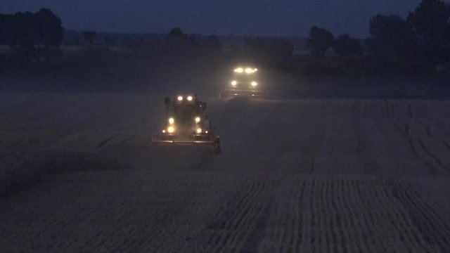combine with lights thresh wheat field in farm in evening. 4K