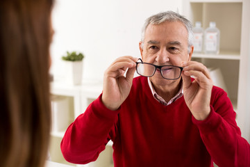 Senior man patient takes glasses aftere change of diopter