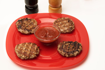 Four ready-made meat cutlets with ketchup and relish on a plate