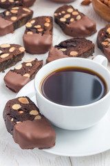 Homemade dark chocolate biscotti cookies with almonds, covered with melted chocolate, and cup of coffee, vertical