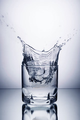 glass of water and ice on a white background with splashes