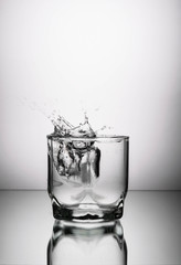 glass of water and ice on a white background with splashes