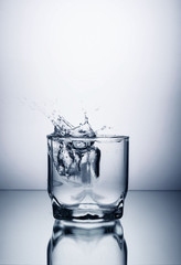 glass of water and ice on a white background with splashes
