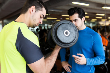 Fototapeta na wymiar Two handsome young men doing muscular exercise in gym.