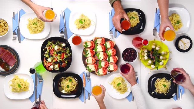 family clanging glasses by the table full of different tasty dishes, top view