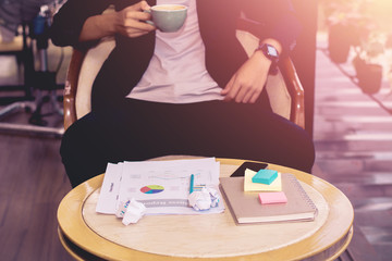 Young businessman looking to relax from work by sipping coffee.