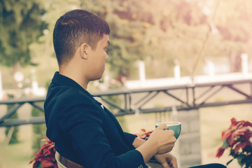 Young businessman looking to relax from work by sipping coffee.