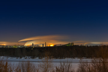 Night winter landscape with starry sky. Industrial area with res