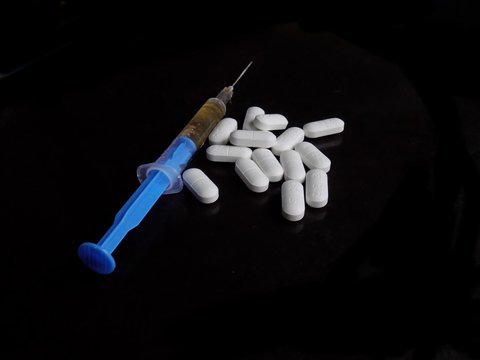 Medical pills and injection on black background