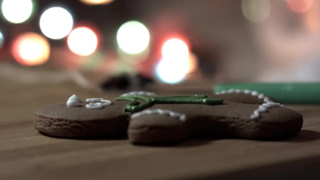 Female hand decorate Gingerbread man cookie with food icing on the table, close up. Bokeh in backgound.